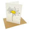 A white seed paper greetings card with a black-lined daisy and yellow center on a brown kraft envelope