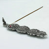 Polished aluminium incense holder with silver peacock feather design and small red gemstone accent for burning sticks