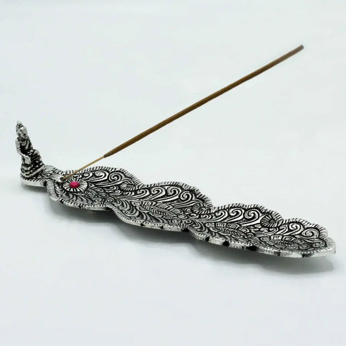 Polished aluminium incense holder with silver peacock feather design and small red gemstone accent for burning sticks