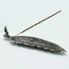Polished aluminium incense holder long shaped with silver intricate swirling patterns and small buddha figurine at one end