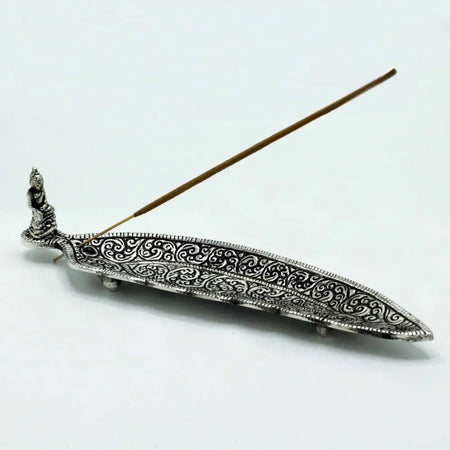 Polished aluminium incense holder long shaped with silver intricate swirling patterns and small buddha figurine at one end