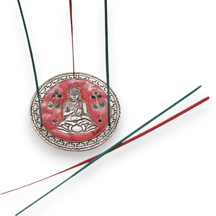 Red and silver polished aluminium incense holder with buddha design enameled details and green and red incense sticks hanging