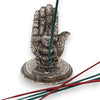 Silver polished aluminium incense holder shaped like a hand with floral engravings and a seated buddha figure in the center