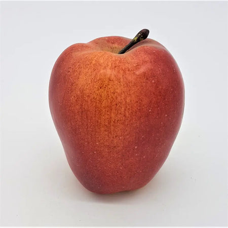 A glossy deep red artificial fruit braeburn apple with slightly speckled skin and a dark brown stem