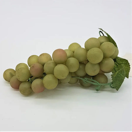 A bunch of premium artificial fruit grapes in green with hints of pink attached to vine and leaves