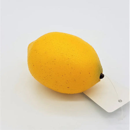 A bright yellow textured artificial fruit lemon with a small black stem and attached white tag