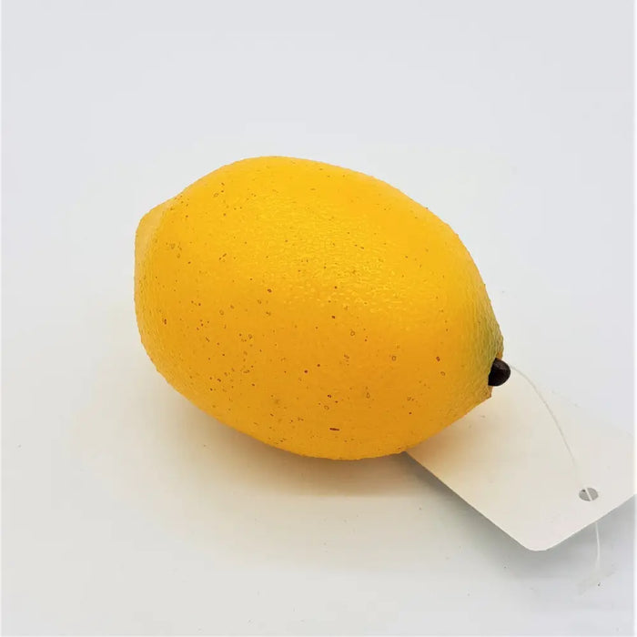 A bright yellow textured artificial fruit lemon with a small black stem and attached white tag