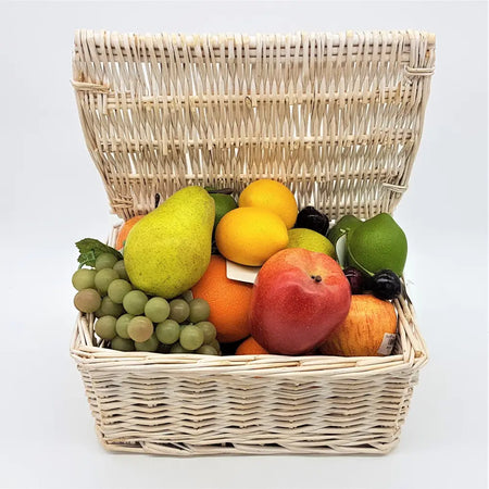 A light beige woven wicker basket filled with colorful premium artificial fruit including a pear