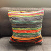 A multicolored rag rug cushion with horizontal stripes in natural greens and warm tones made from indian rag rugs