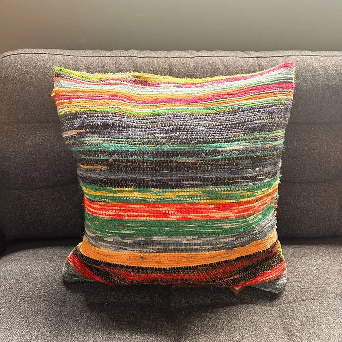 A multicolored rag rug cushion with horizontal stripes in natural greens and warm tones made from indian rag rugs