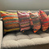 Vibrant rag rug cushion covers with rich reds and multicolored stripes in orange yellow and green woven texture