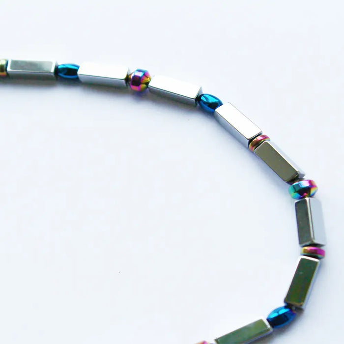 A sleek rainbow hematite peninsular magnetic bracelet with silver rectangular beads and iridescent spherical accents
