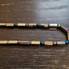 A magnetic therapy rainbow hematite peninsular necklace with gold silver beads and iridescent blue pink green accents