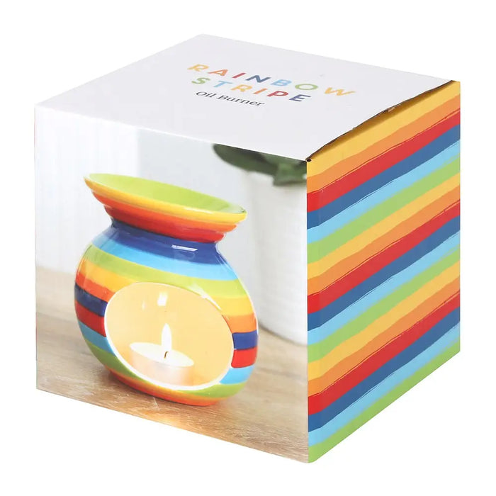 Rainbow stripe ceramic oil burner with circular cutout holding a lit tealight candle for home fragrance