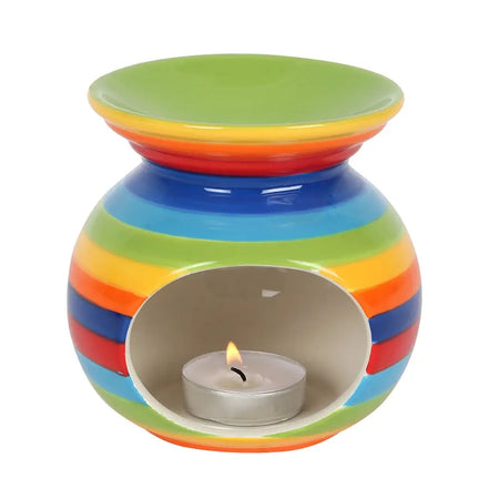 Rainbow stripe ceramic oil burner with rainbow stripes and a lit tealight candle inside for aromatherapy use