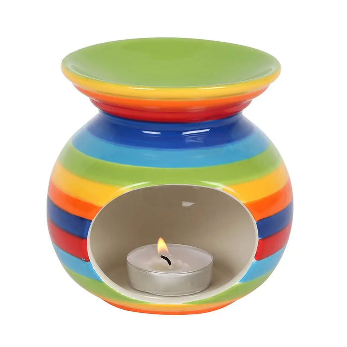 Rainbow stripe ceramic oil burner with rainbow stripes and a lit tealight candle inside for aromatherapy use