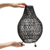 Black woven rattan table lamp with diamond-pattern lattice design and small black spherical feet plug fitting table lamp