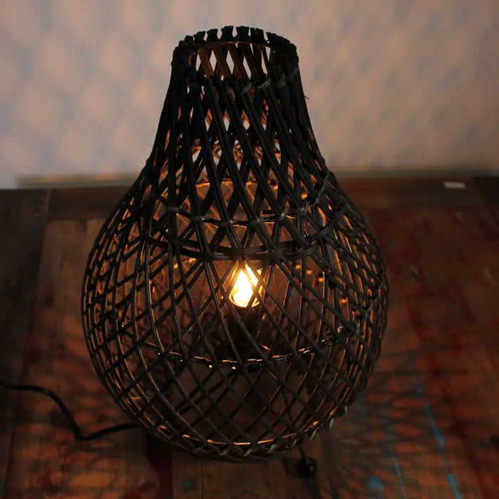 Black rattan table lamp with dark woven rattan geometric lattice lampshade and exposed bulb plug fitting