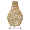 Natural rattan table lamp with a tapered vase shape and three golden ball feet casting delicate shadows