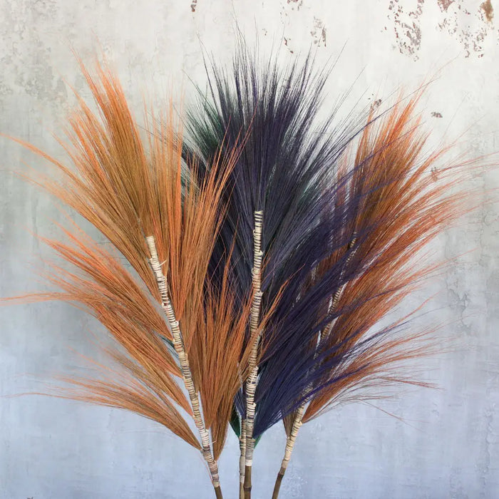 A bundle of dried rayung grass with coral orange and deep purple feathery plumes tied at the base in a set of 3
