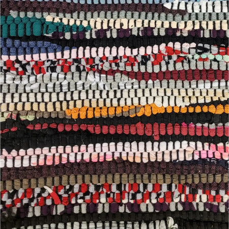 A colorful chindi rag cushion cover with red orange black white and teal recycled fabric strips in a patchwork pattern