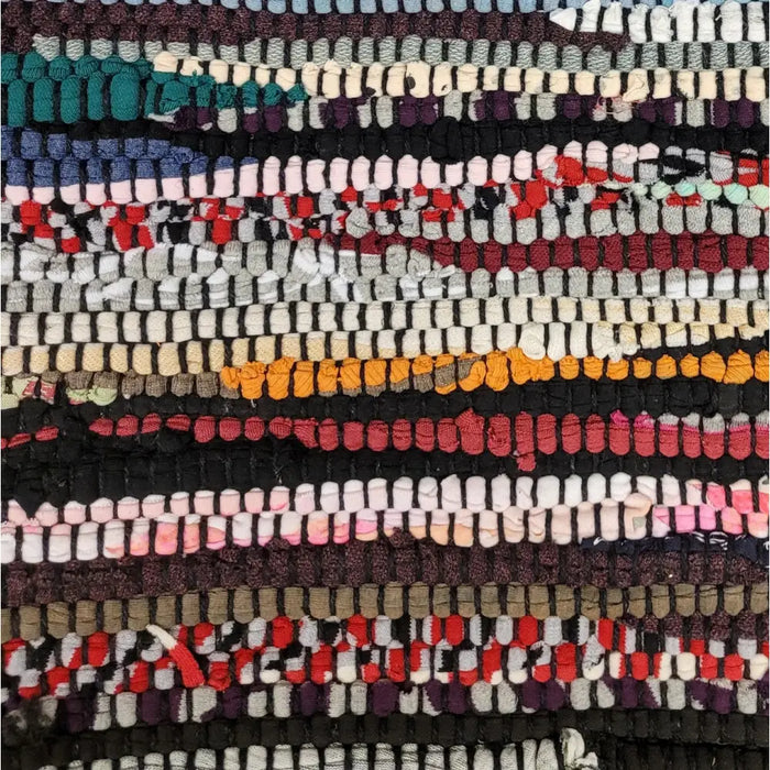 A colorful chindi rag cushion cover with red orange black white and teal recycled fabric strips in a patchwork pattern