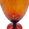 A recycled glass wine glass in amber with a textured hammered finish and a deep red base for serving wine