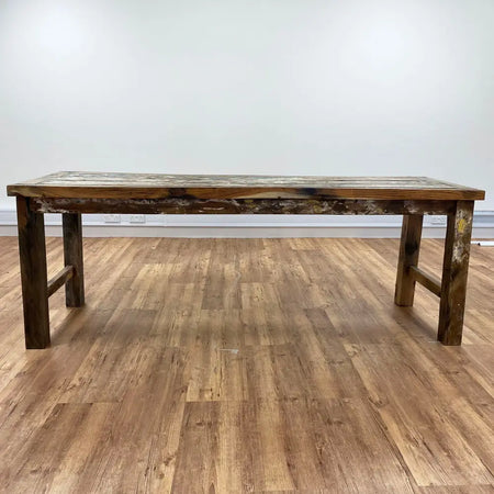 Rustic dining table with weathered reclaimed teakwood top and dark stained legs for indoor use