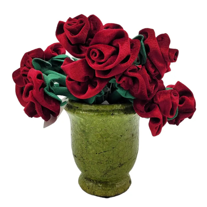 A bouquet of vibrant red fabric roses with green stems in a crackle glazed terracotta olive green vase