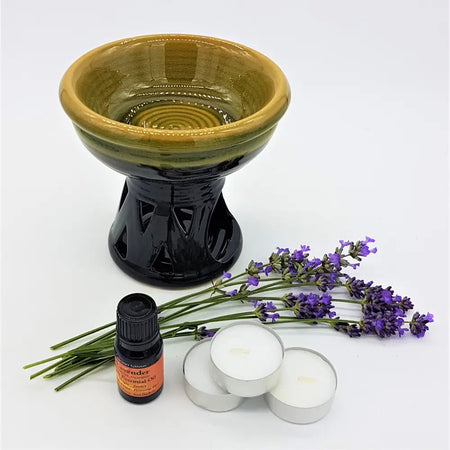 A ceramic oil burner with a glossy black base and gradient green bowl in a relaxing lavender essential oil kit