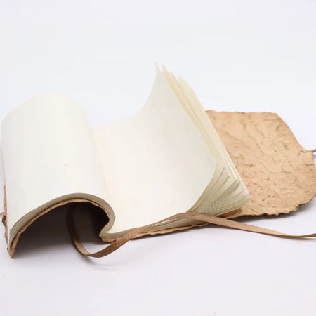 Handmade rolled leather travel notebook with textured brown leather cover cream pages and matching leather ribbon tie
