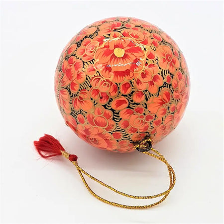A hand-painted papier maché bauble with orange and black floral design gold tassel and braided cord