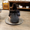 Woman in black and white striped top sitting cross-legged on a round 90cm jute and recycled denim rug