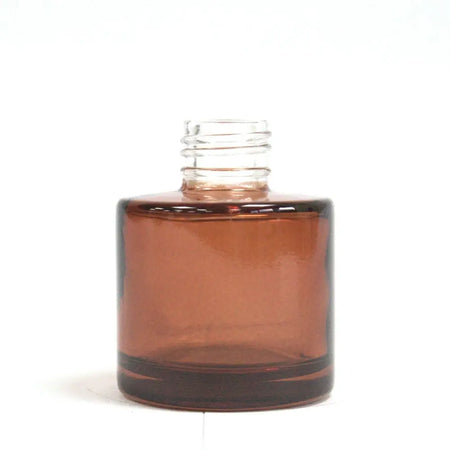 A clear amber round reed diffuser bottle with brown tint and screw cap neck for bamboo reed diffuser use