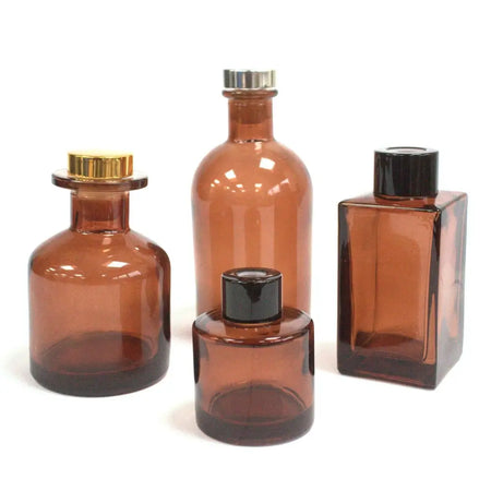 Set of four round reed diffuser bottles in amber glass with gold silver and black screw caps for bamboo reed diffuser