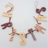 A rustic wooden christmas wall hanging with cream and maroon painted letters and red white gingham ribbons