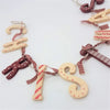 A rustic wooden christmas wall hanging with red and beige letters decorated with patterns and tied by a plaid ribbon