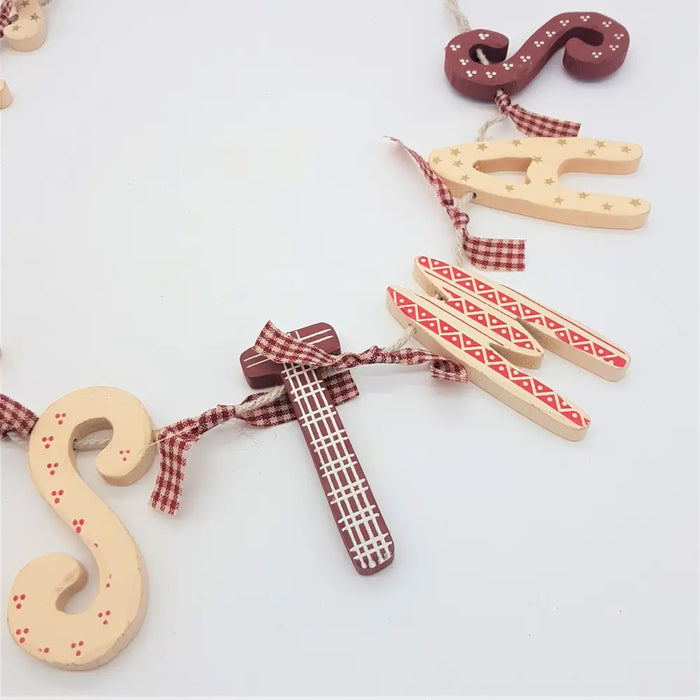 Rustic christmas wall hanging with wooden letters and guitar ornaments tied with red and white checkered ribbon