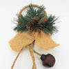 Rustic jingle bells hanging decoration with burlap bow, pine needles, pinecones, red berries, and dark bell hanging on rope