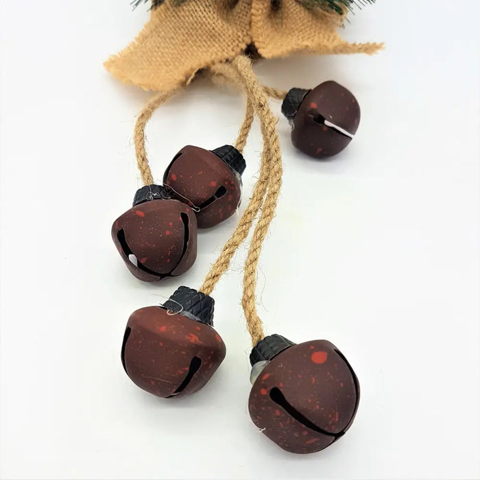 Five dark brown speckled jingle bells with black caps hanging from rustic twine in a rustic jingle bells decoration