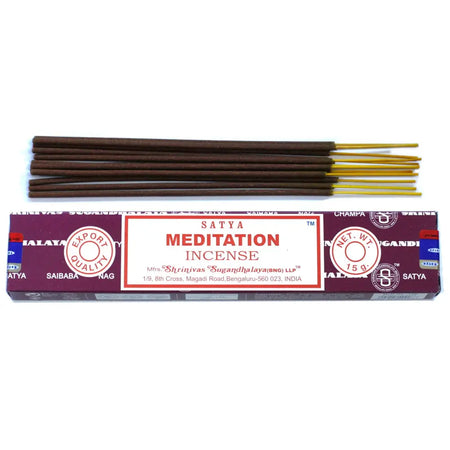A box of satya incense sticks for meditation with a maroon white label and gold-tipped sticks arranged neatly above it