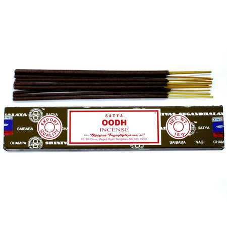 A pack of satya incense sticks with dark brown wooden sticks and golden tips next to a red and white labeled box