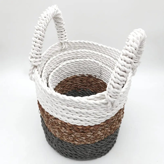 A set of three seagrass baskets in grey natural and white with striped pattern and thick rope handles