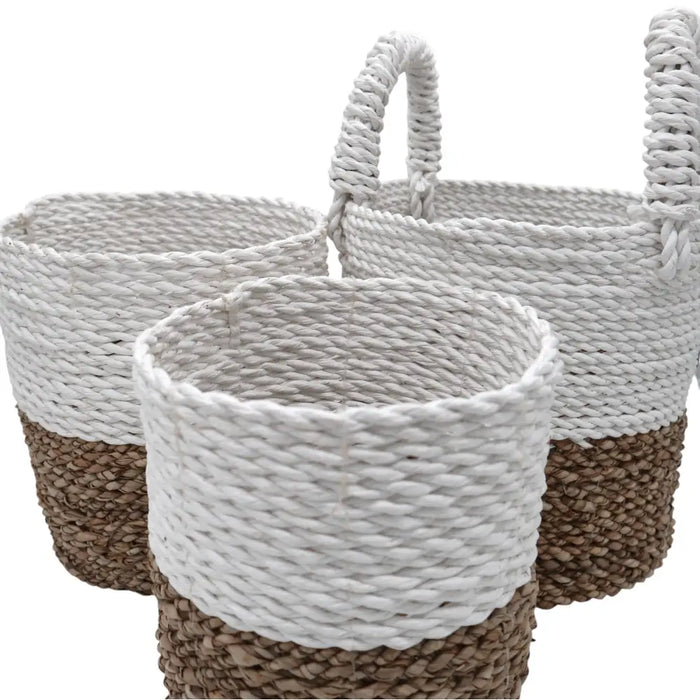 A set of 3 natural and white woven seagrass baskets with braided handles for storage and organization