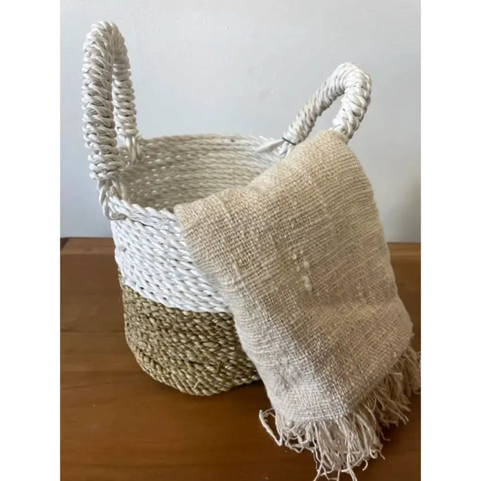 White and beige woven seagrass basket with rope handles part of a natural and white set of 3 baskets