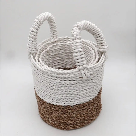 A set of three seagrass baskets with natural brown and white braided design and white rope handles