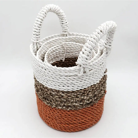 A seagrass basket set of 3 with a woven orange natural and white color block design and sturdy handles