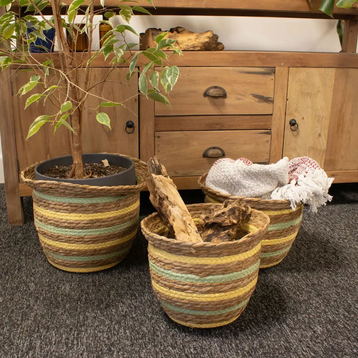 Three woven straw baskets with yellow green and brown stripes made of seagrass and straw in a set of 3