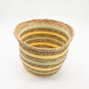 A woven set of three straw baskets with horizontal stripes in natural brown yellow and light green colors