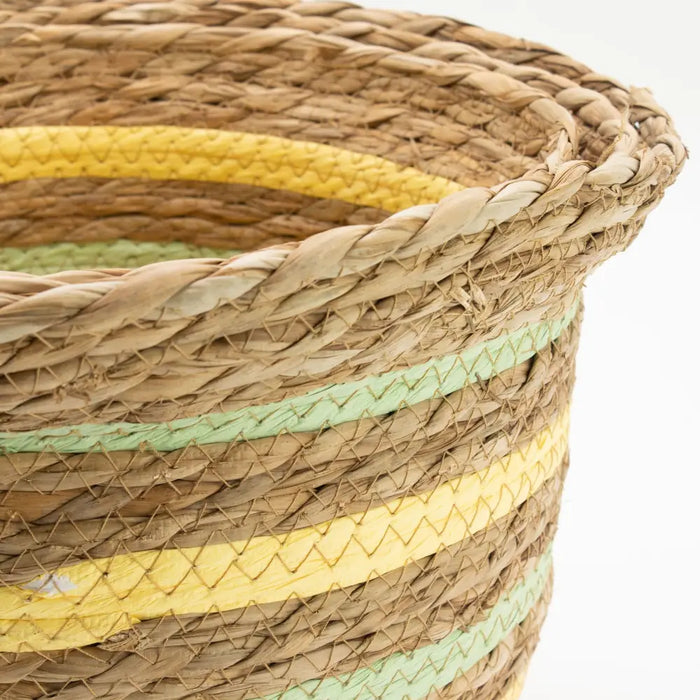 A set of three straw baskets woven from natural seagrass with yellow and green decorative stripes